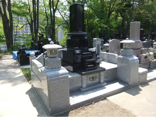 渋川市内寺院に建立された、クンナムと中国産白御影を組み合わせた和型墓石。黒と白のコントラストが際立つ重厚なデザインに石灯籠を備えた施工例。