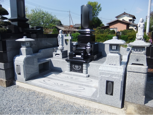 前橋市内の寺院に建立された、クンナム×中国産白御影の和型墓石。蓮模様の参拝スペースと石灯籠、石仏を配置した上質なデザイン。