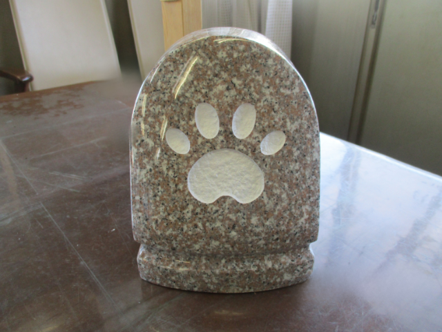 茶系御影石663を使用した肉球マーク彫刻入りの小型ペット墓石。室内テーブル上に置かれたかわいらしい供養石。